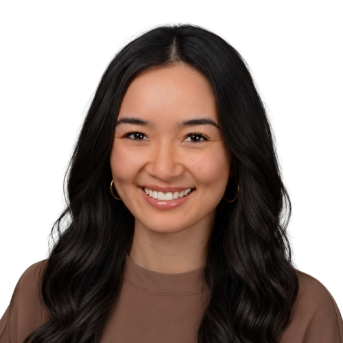 Smiling woman with long dark hair in a brown top, hoop earrings, head-and-shoulders shot against a white background